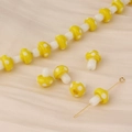 Macro detail of yellow polka dot mushroom glass beads with gold metal T-pins on velvet - Yellow