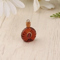 Macro shot of miniature resin XO brandy bottle pendant with gold loop on wood surface - Coffee