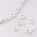 Detailed view of fish-shaped ceramic beads with blue evil eye motifs for DIY jewelry - Pearl White