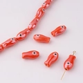 Macro detail of handmade orange fish-shaped ceramic beads for DIY jewelry making - Bright Orange