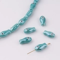 Macro detail of turquoise handmade fish-shaped ceramic beads for DIY jewelry making - Turquoise Green