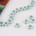 Macro detail of star-shaped ceramic beads in pale green with smiley faces for DIY jewelry - Light Cyan-Green