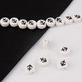 Macro detail of white ceramic beads with black Sagittarius zodiac symbols for DIY bracelets - Sagittarius