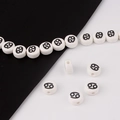 Macro shot of white round ceramic beads with black zodiac sign for DIY bracelet jewelry - Cancer