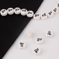 Detailed macro view of white ceramic Capricorn zodiac beads with black printed symbols - Capricorn