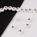 Macro detail of white ceramic bead with Aries zodiac symbol and precise drill hole - Aries