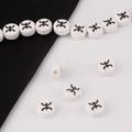 Detailed view of white ceramic beads with black ethnic symbols for DIY jewelry making - Pisces