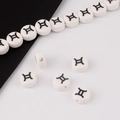 Macro shot of white ceramic Gemini zodiac beads for DIY jewelry making and bracelets - Gemini