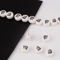 Close-up of white round ceramic beads with black Virgo zodiac sign for DIY bracelets - Virgo
