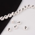 Macro view of white ceramic zodiac beads with black Scorpio symbols for DIY jewelry - Scorpio