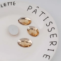 Macro shot of 18x25mm champagne oval faceted acrylic rhinestones with flat silver back - Standard Spec / Champagne