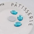 Detalle de los diamantes de imitación acrílicos azul lago de 18x25mm en un plato blanco - Especificación Estándar / Aguamarina
