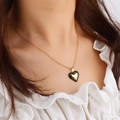 Elegant gold and black double heart pendant necklace on female model in white top - Black