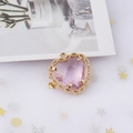 Macro shot of pink heart-shaped crystal pendant with gold lace metal frame and loop - Pink
