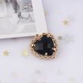Detail view of heart-shaped pendant with black zircon gemstone and golden mesh frame - Black