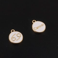 Macro de pendentifs Cancer dorés avec émail blanc sur un fond texturé noir élégant - Cancer / Blanc