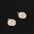 Gros plan sur breloques Capricorne en émail blanc et bordure dorée pour bijoux - Capricorne / Blanc