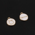 Macro view of gold-plated Taurus zodiac charms with white enamel for DIY jewelry making - Taurus / White
