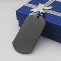 Nahaufnahme der mattschwarzen Edelstahl-Hundemarke auf einer blauen Schmuckschachtel - 50mmx28mmx2mm / Schwarz