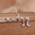 Dettaglio di un set di 5 orecchini a stella e luna su un espositore di legno scuro - Argento