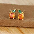 Macro view of fruit-shaped stud earring with orange cubic zirconia and green leaf detail - Orange