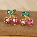 Macro detail of cherry stud earrings with 18K gold plating and red heart-shaped crystals - Cherry