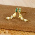 Macro shot of gold fruit stud earrings with emerald green and yellow zircon stones - Banana