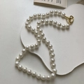 Gros plan détaillé d'un collier de perles grises rondes avec un fermoir OT doré - 8mm Perles Multicolores Blanches (Style Noué)