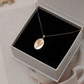 Collier ovale en nacre dorée avec muguet présenté dans son coffret cadeau - Muguet de Février