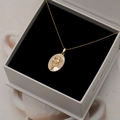 Collier pendentif ovale en nacre dorée avec sculpture florale dans un écrin noir - Oeillet de Mai