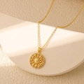 Gros plan du pendentif tarot soleil doré avec zircons sur un support de pierre - Soleil et lune