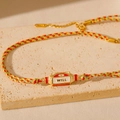 Gros plan du bracelet tissé coloré avec breloque WILL et détail de l'œil maléfique - Evil Eye - Rouge