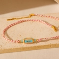 Détail du bracelet tissé rose et blanc avec breloque œil porte-bonheur et gravure WILL - Œil Maléfique - Rose