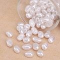 Irregular white baroque pearl beads spilling from a glass jar for DIY jewelry making - Flat Oval Bead Style (#57)