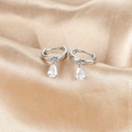 Detail view of silver hoop earrings with teardrop zirconia on champagne silk fabric - White Pendant (E1045-Silver White)