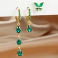Macro-opname van 18k gouden oorbellen met smaragdgroene peervormige stenen en vlinderknopje - Vlinder Waterdruppel Stijl / Goud en Groen