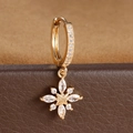 Close-up of golden star drop earrings with sparkling cubic zirconia on a leather display - Starburst Snowflake Style (E1653-1) / Gold