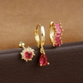 Detail eines dreiteiligen goldenen Ohrringsets mit roten Zirkonsteinen und Tropfenanhänger - Gold-Rosarot