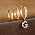 Macro-detail van gouden letter G oorbellen set met zirkonia op een leren ondergrond - Letter G Stijl (Y26056-G)