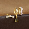 Makroaufnahme von vergoldetem Ohrring-Set mit grünem Tropfen und lila Zirkonia-Details - Gold
