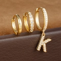 Macro-detail van gouden S925-oorbellen met zirkonia en een letter K-hanger - Letter K Stijl (Y26056-K)