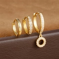 Detail van drie vergulde S925-oorbellen met zirkonia op een leren standaard - Letter O Stijl (Y26056-O)