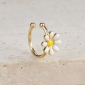 Close-up of golden C-shaped daisy earrings with white petals on a beige stone surface - Little Daisy Style (E1684 Gold)