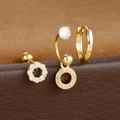 Dettaglio di tre orecchini dorati con zirconi, cerchi e perni su base in pelle marrone - Zirconia Rotonda - Oro