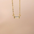 Macro detail of gold necklace with rectangular translucent gemstone pendant on skin - October