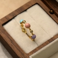 Vue macro détaillée d'une bague dorée avec perles colorées et zircon en boîte de luxe - Style Rond / Or