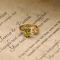 Makro-Detail des vergoldeten offenen Rings mit herzförmigen grünen und weißen Steinen - Gold Herz Zirkon (18K Gold)