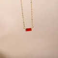 Détail d'un collier doré avec pendentif en zircone rouge rectangulaire, pierre de naissance - Janvier