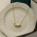 Detail of gold MAMA necklace with pink teardrop birthstone on a ceramic plate - October