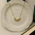 Detail of gold MAMA letter necklace with purple teardrop birthstone on ceramic plate - June